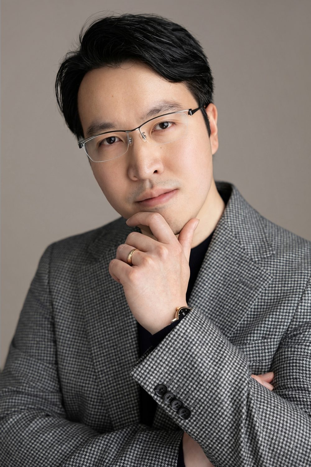 Ed Hung, hand to chin, in a grey houndstooth jacket